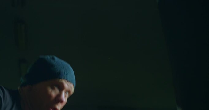 Slow Motion Of Boxer Training With Punching Bag In Dark Gym. Concept Of Strength, Discipline And Endurance