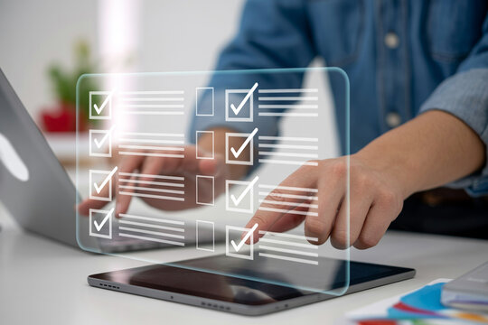 Person completing an online checklist with digital check marks on transparent screen, business productivity.