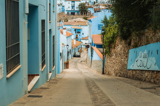 View of the narrow streets and vibrant blue buildings of the Smurf Village with terracotta roofs and stone walls in Juzcar, Andalusia, Spain.