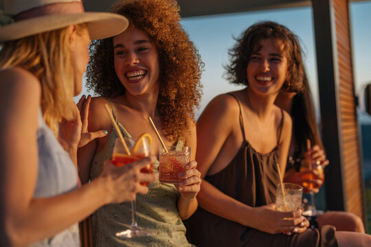 Women friends enjoying cocktails at summer sunset party