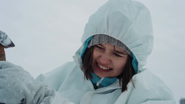 Female researcher in protective hood signaling for rescue amid icy plain near abandoned study site, holding radio, windblown hair, determined expression, urgent beacon attempts and faint hope