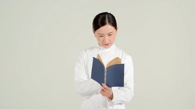 Portrait of chinese medicine physician practitioner female doctor carefully reading and thinking information from an ancient book, study materials oriental medicine, continuous learning development