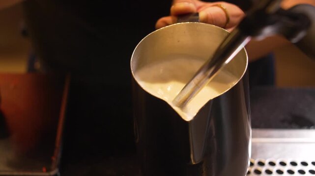 Barista Frothing Milk with Steam Wand for Latte or Cappuccino at Specialty Coffee Shop