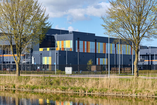Middenmeer, Netherlands - 14 April 2026: View of Microsoft Datacenter Western Europe AMS Campus 13 with its colorful facade reflected in a canal under a blue sky.