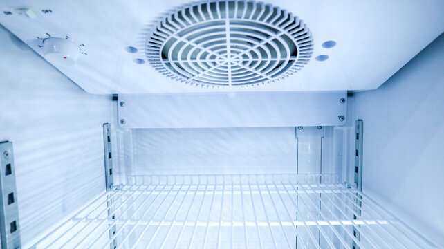 Close up internal view looking up at the cooling fan system and top shelf of an empty showcase fridge