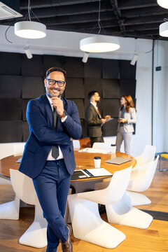 Confident businessman in suit networking with colleagues in modern office during a corporate meeting, leading successful team collaboration