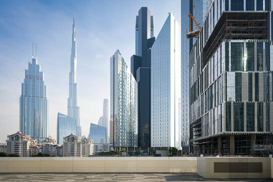 Dubai, United Arab Emirates - 22 April 2023: View of the Burj Khalifa and modern skyscrapers in the downtown skyline with people walking on the terrace under a clear blue sky.