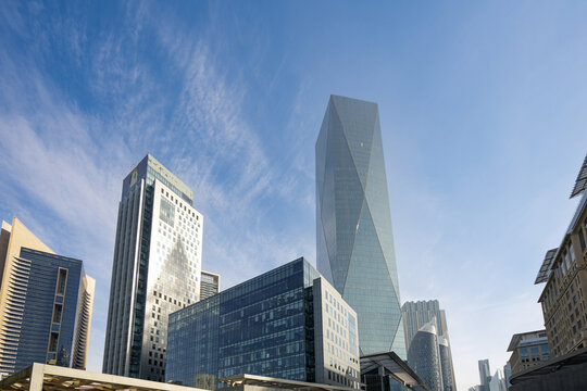 Dubai, United Arab Emirates - 22 April 2023: View of modern skyscrapers in the DIFC district featuring the geometric ICD Brookfield Place tower under a clear blue sky.
