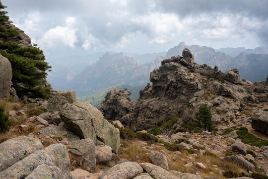 Dramatic granite peaks of the Bavella Needles near Quenza in Corsica, France, beneath a dark cloudy sky. Rugged mountain landscape with striking rock formations.