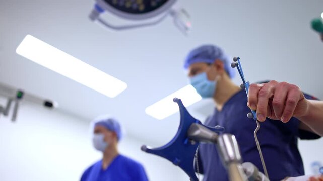 Surgeon holding cranial fixation device in operating room.