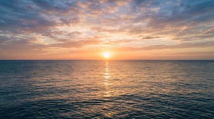 Fototapeta premium Beautiful sunset over the ocean with golden sun reflection on the calm water surface during a peaceful evening