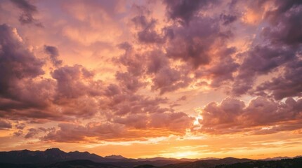 Fototapeta premium Beautiful orange and purple sunset sky with clouds over distant mountain silhouettes