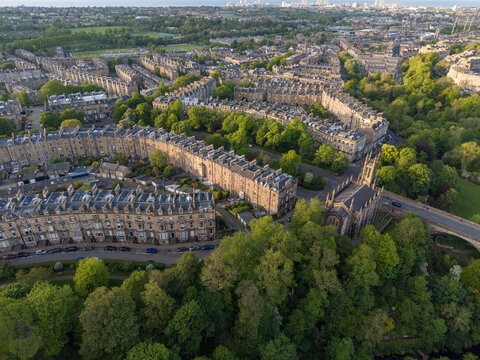 Aerial view of curved Georgian stone terraces and the Dean Parish Church surrounded by lush green trees in Edinburgh, Scotland, United Kingdom.