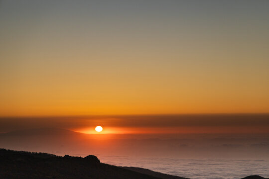 Bright sunset above clouds and calima