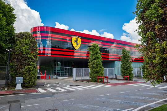 Maranello, Italy, May 15, 2026. The modern red and black glass facade of the Ferrari factory entrance featuring the iconic prancing horse logo
