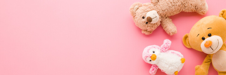 Colorful soft animal toys on light pink table background. Pastel color. Closeup. Wide banner. Empty place for text. Flat lay. Top down view. © fotoduets