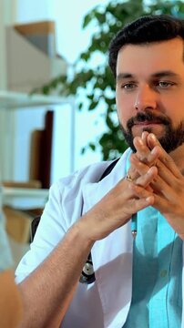 Indian Asian handsome male doctor discussing a medical case with a senior old-aged male patient across the table in his OPD, carefully deciding the best line of treatment in a cozy, modern clinic