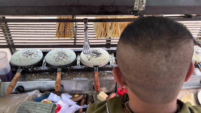 Asian man selling an Indonesian crunchy pancake named Leker, made from flour with chocolate, cheese, and slices of banana topping