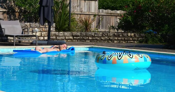 Beautiful young girl enjoying lounging in the swimming pool during heatwave