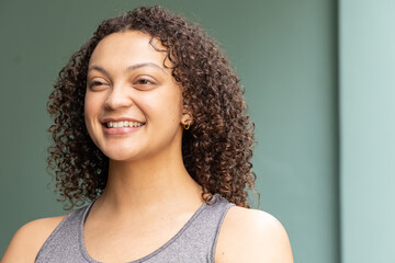 African American woman smiling in studio, wearing grey sleeveless tank top and gold hoop earring © wavebreak3