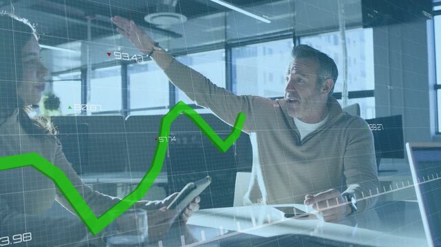 Lead man speaking, gesturing causing finance chart crossing frame as woman using tablet about data