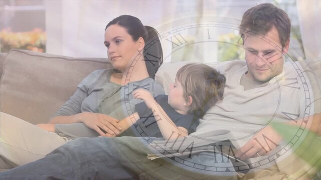 Child shifting, leaning into man; man glancing at mag, woman watching, clock marking family time