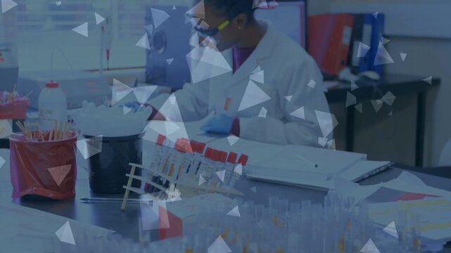 Lab tech checking records then inspecting tubes and noting results while triangles obscure bench