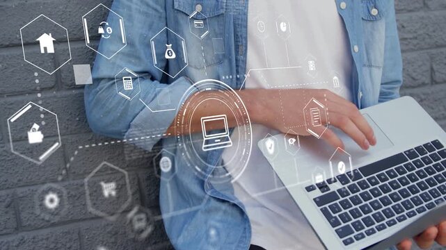 Man leaning on gray wall reacting to incoming holo HUD, typing on laptop, marking finance icons