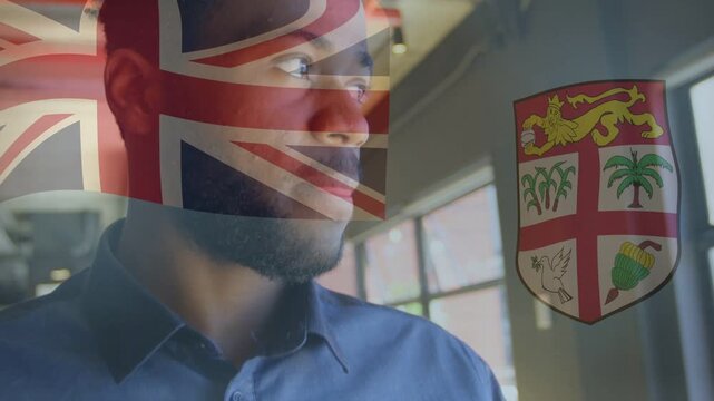 Man standing office window seeing light, turning to camera smiling, UK flag and shield overlaying