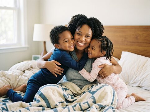 Filhos abra&ccedil;ando sua m&atilde;e na cama