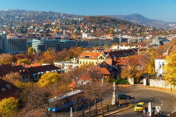 Obraz premium Sweeping panoramic cityscape view of Budapest, Hungary, showing dense European architecture nestled on hillsides during beautiful autumn season and vibrant urban life