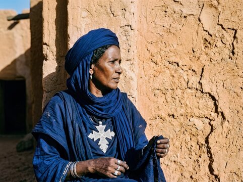 Nomadic Woman in Traditional Attire: A portrait of a nomadic woman from North Africa, her face etched with wisdom, adorned in a vibrant blue djellaba and headscarf.