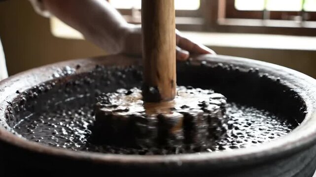 Traditional oil extraction process pressing seeds with wooden ghani. artisan cold pressed organic oil production.