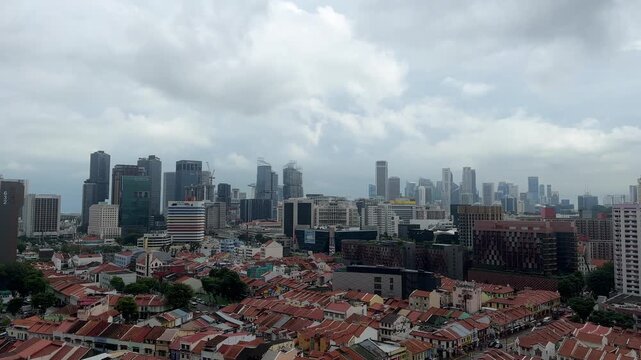 Singapore Little India timelapse over terracotta shophouse rooftops with CBD skyline towers and fast moving overcast monsoon clouds, heritage district elevated view tropical Asian city 4K B-roll