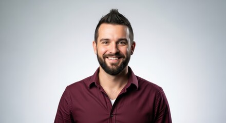 Obraz premium Portrait of a Confident Smiling Young Man with a Beard and Stylish Mohawk Haircut in a Maroon Shirt