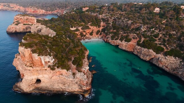Cala des moro beach, mallorca, turquoise waters and rocky cliffs at sunset