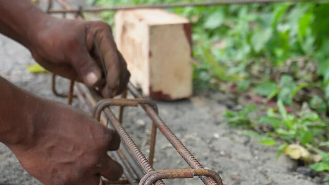 Hands Tying Steel Rebar with Wire at Construction Site