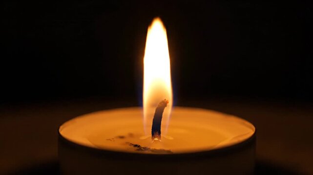 Candle flame flickering against a dark background in close up
