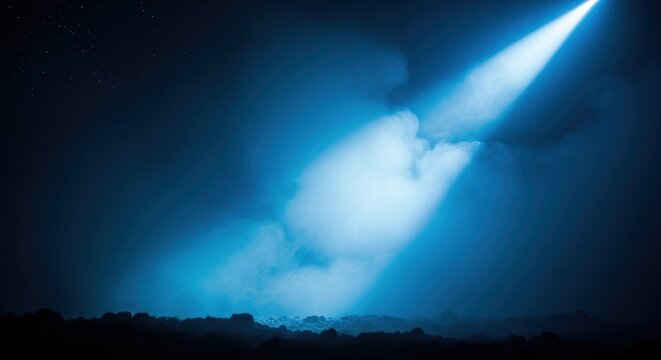 Dramatic Blue Spotlight Beam Shining Through Night Sky Clouds Over Dark Rocky Terrain Landscape
