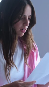 Young woman looking shocked and distressed while reading a document, her expression changing from surprise to deep disappointment and sadness after receiving unexpected bad news