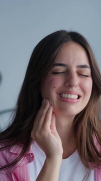 Unhappy young woman feeling unwell and suffering from a severe toothache, touching her cheek with a painful expression and needing urgent dental care for her oral health problem