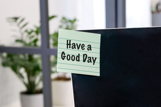 Green note on dark surface reads Have a Good Day. Soft lighting highlights leafy plant in blurred background.