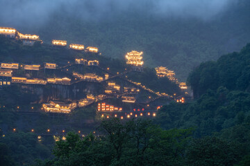 Fototapeta premium Beautiful traditional architecture illuminated with warm lights at night in the scenic mountains of Wangxian Valley in Jiangxi China