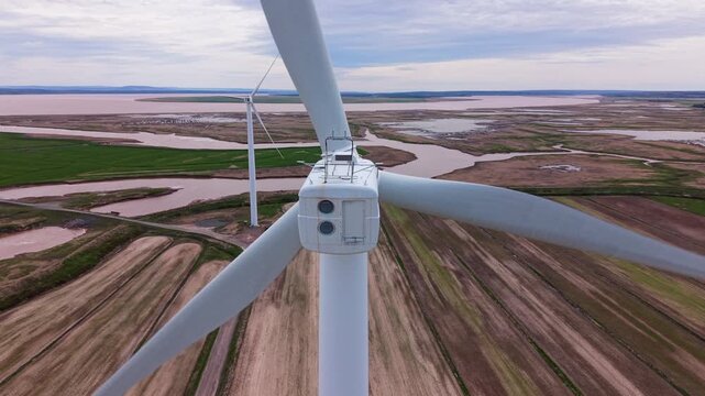 An aerial view of a field with windmills near a river and the ocean in Nova Scotia. The windmills are part of the renewable energy landscape that shapes the area