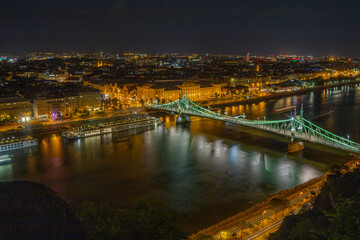 Fototapeta premium Liberty Bridge and theUniversity of Economics campus at night in Budapest