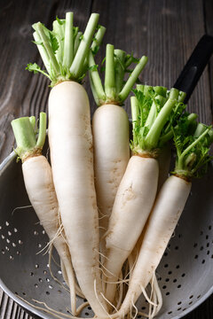 Fresh daikon radish in metal colander, white radish, washed vegetables