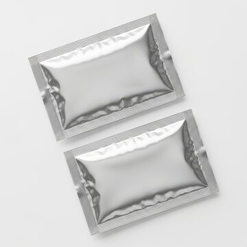 Two sealed foil packets on a white background, possibly containing food or product samples.