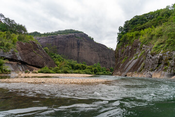A calm river flows between the dramatic rocky cliffs of the Wuyi Mountains in Fujian China © AS_SleepingPanda