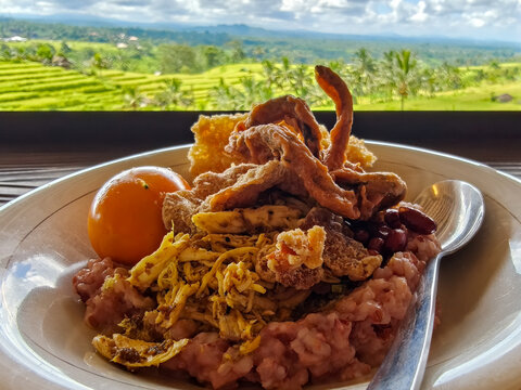 Balinese rice dish nasi campur served on red rice with panoramic green rice terraces background