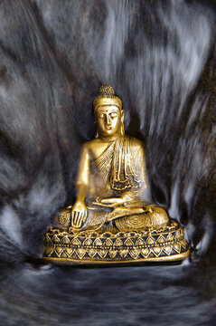  Eine Buddha Skulptur sitzt am flie&szlig;enden Wasser